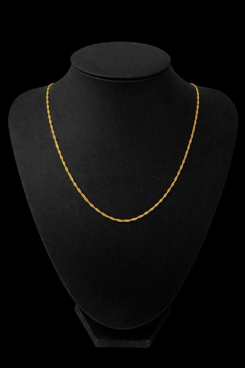 Silver chain necklace displayed on a black mannequin bust against a dark background
