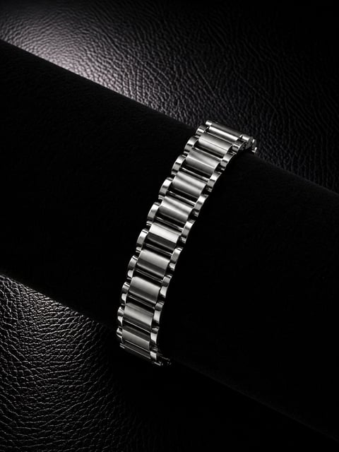 Silver metal watch bracelet displayed on black leather background