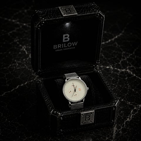Brilow silver minimalist watch with mesh band displayed in black branded case on marble surface
