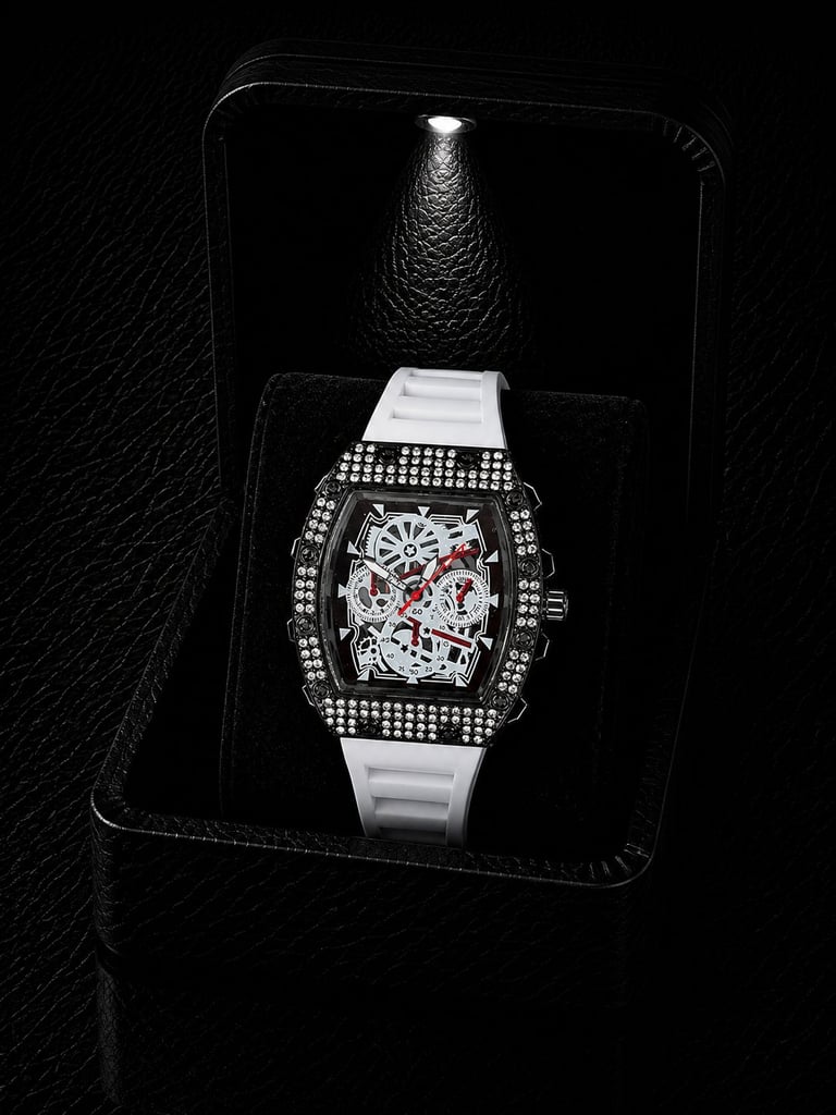 Luxury diamond-encrusted watch with white rubber band and ornate skeleton face displayed on black velvet in elegant packaging