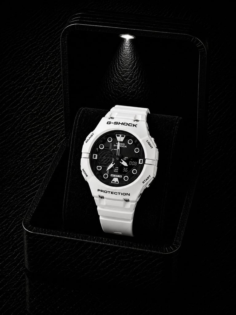White G-Shock digital watch with black dial displayed in a black presentation box against a textured background