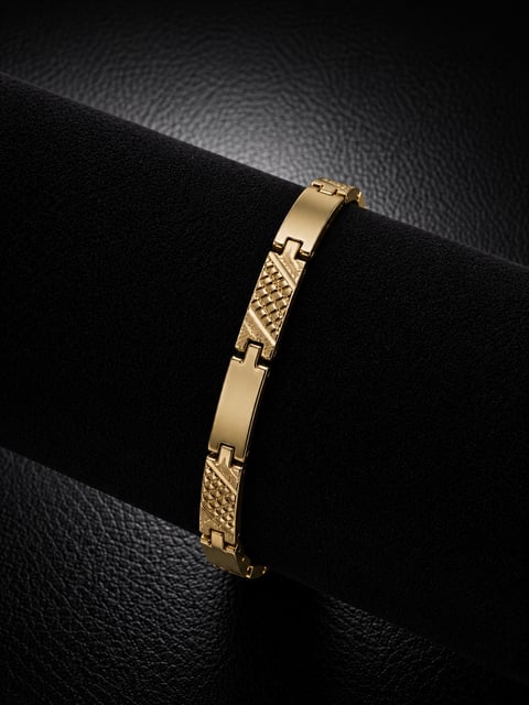 Gold-toned link bracelet with alternating textured and polished segments displayed on black fabric