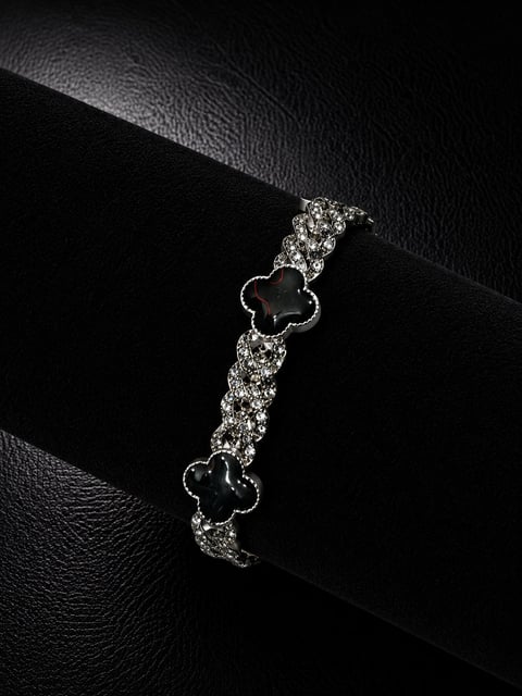 Silver bracelet with black clover charms on black leather strap, displayed on black textured background