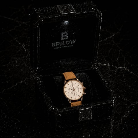 Bpilow chronograph watch with white dial and tan leather strap displayed in black branded box on dark marble background