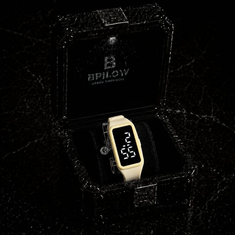 Cream-colored digital watch with black display in open B.Pillow branded box on textured dark background