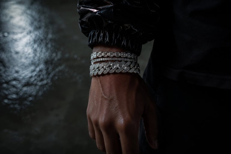 Collection of metal chain bracelets in silver and gold tones arranged on dark textured surface