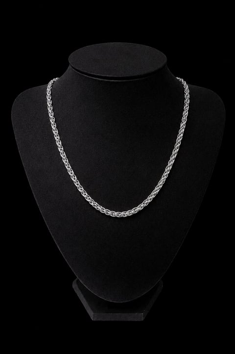 Silver chain necklace displayed on a black velvet bust form against a dark background