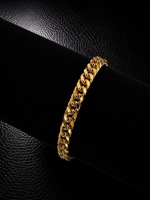 Gold curb chain bracelet on black leather background, displaying luxury jewelry design