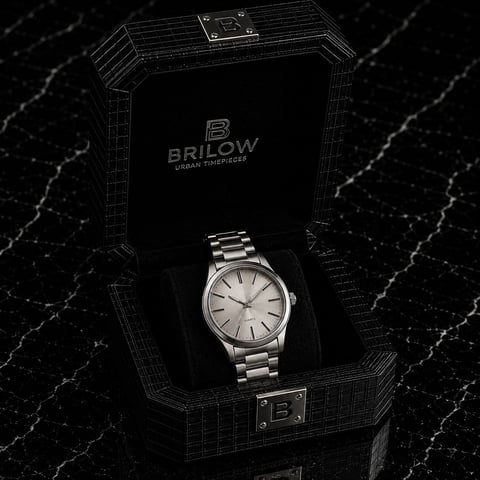 Brilow silver stainless steel watch displayed in an open black branded box on a textured dark fabric background