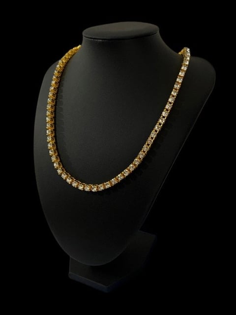 Gold rhinestone chain necklace displayed on a black mannequin bust against a dark background