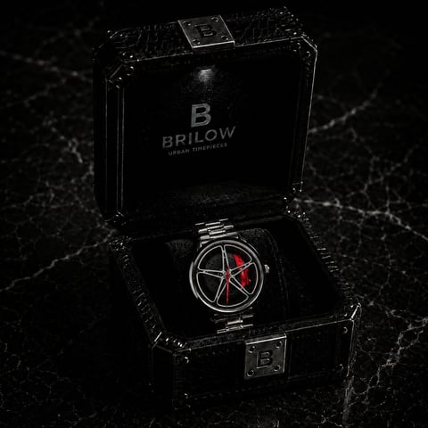 Brilow luxury watch with red accents displayed in open black case on marble surface