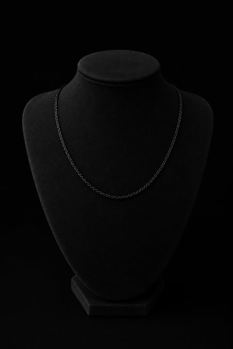 Black velvet jewelry display bust with empty chain necklace holder against dark background